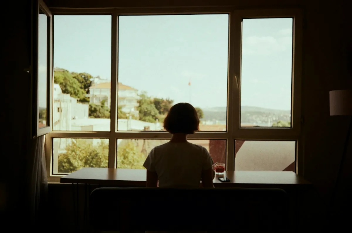 Someone sitting quietly, looking out the window.
