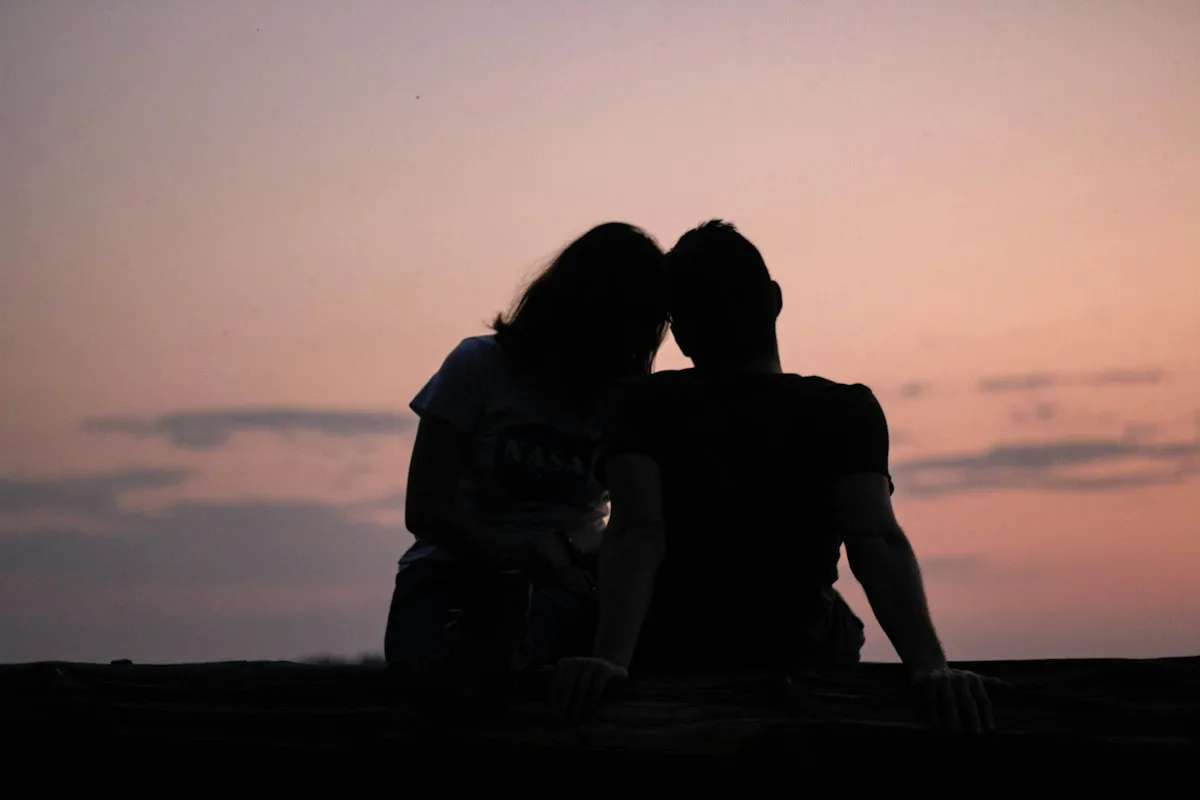 Silhouette of two people, one just slightly more dominant in the frame than the other.