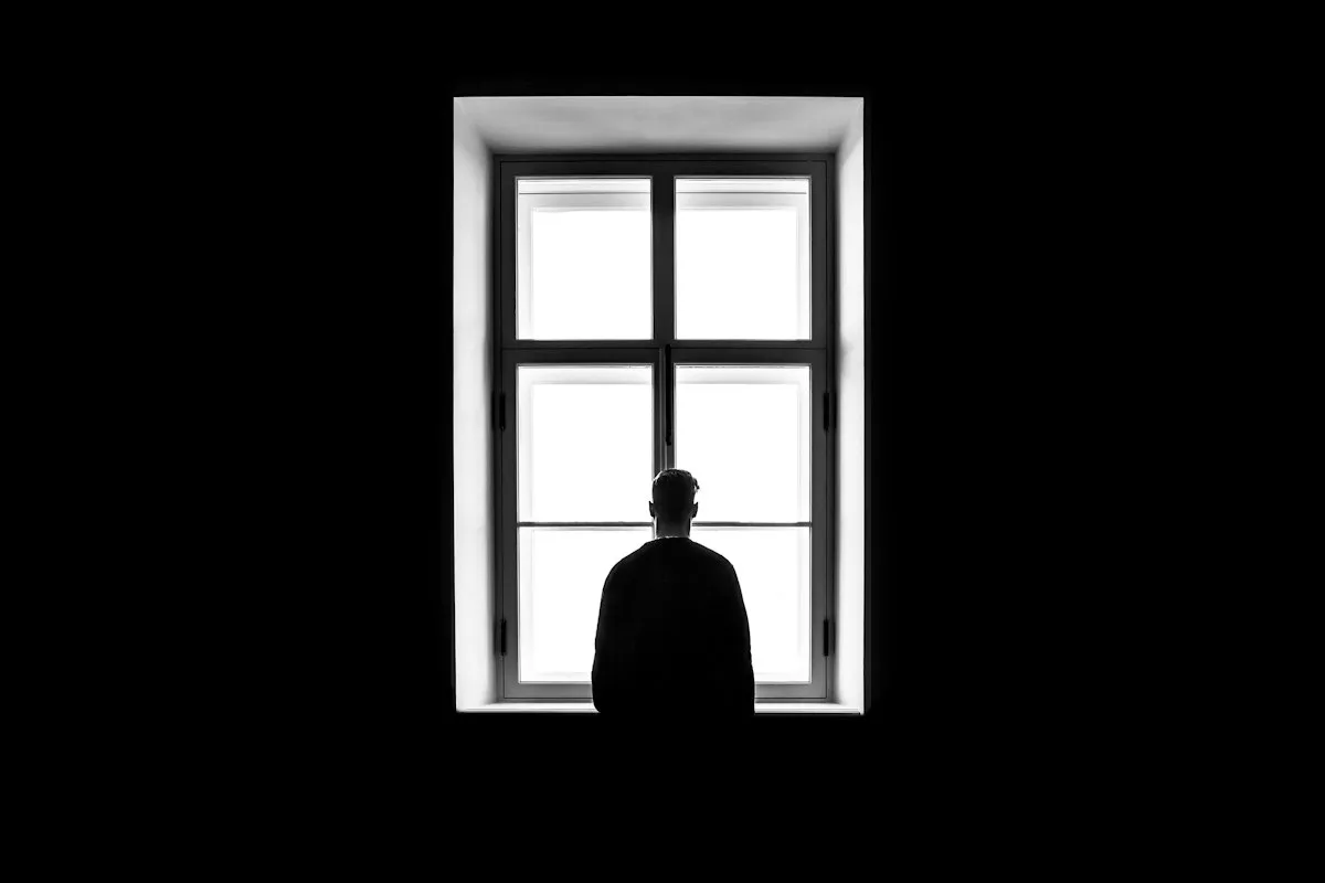 Man standing thoughtfully in front of a window.