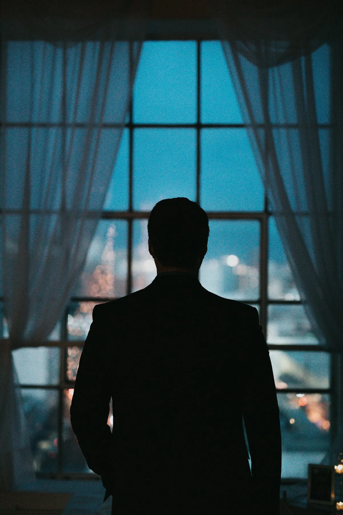 Silhouette of someone standing lost in thought by the window.