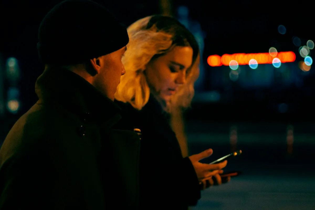 A couple both looking at a phone instead of at each other.
