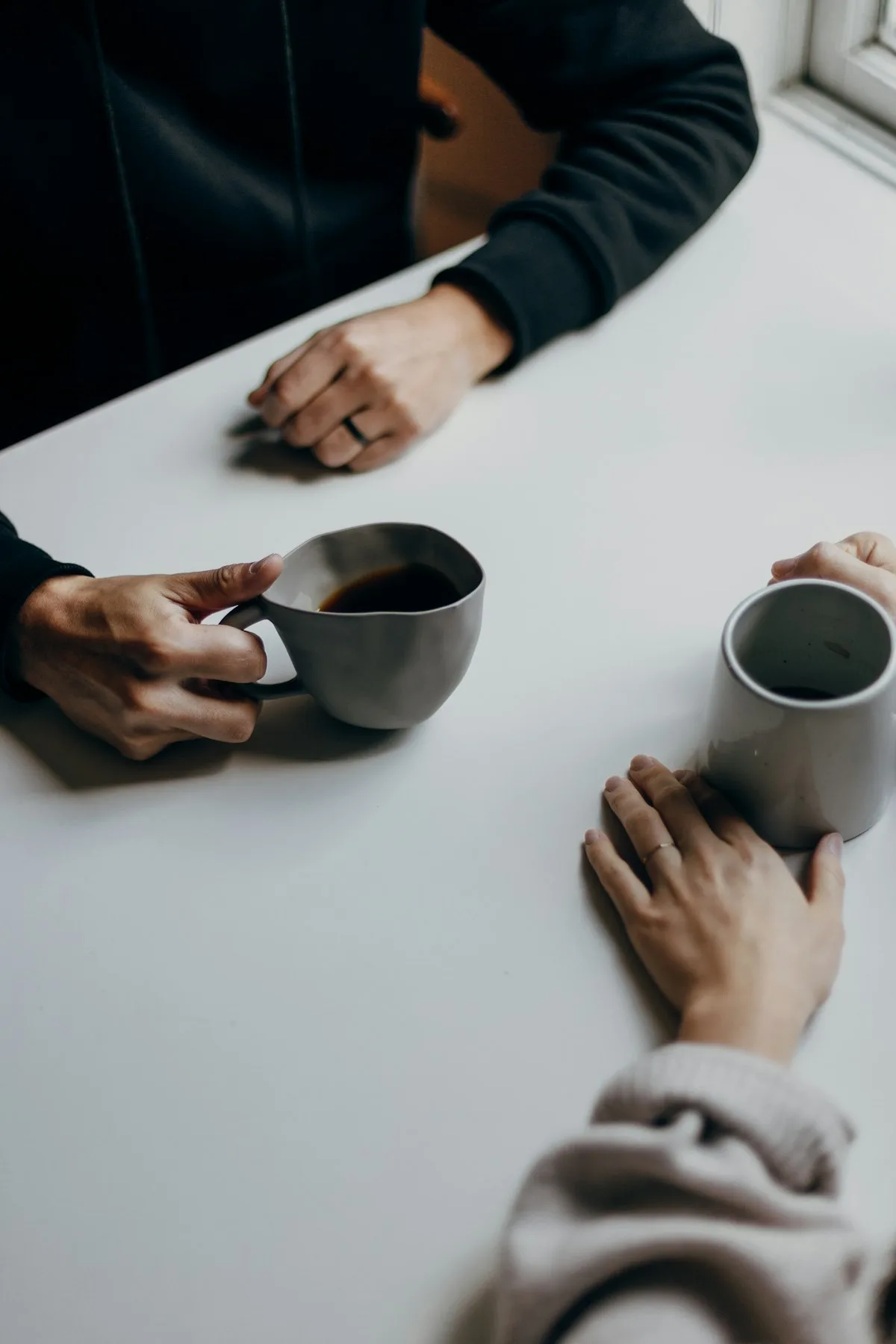 Two people talking at a table over coffee.