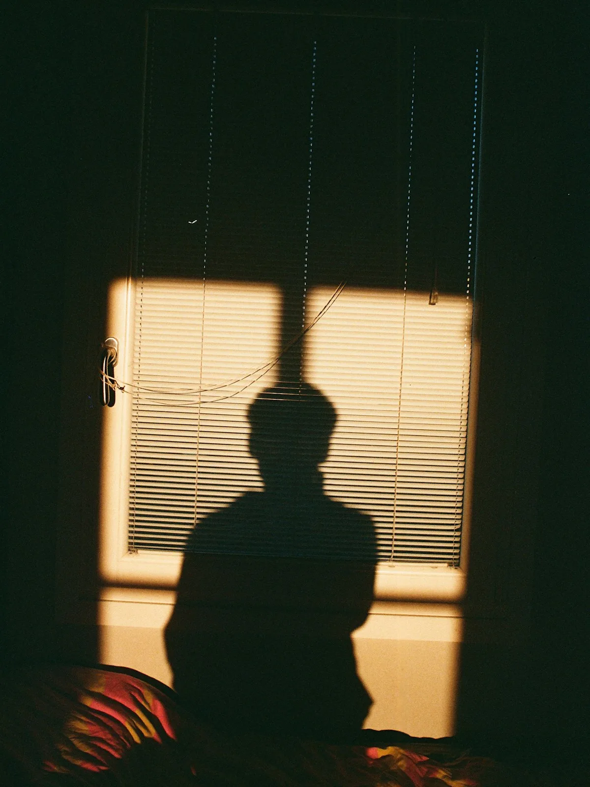 The shadow of a figure by a window.