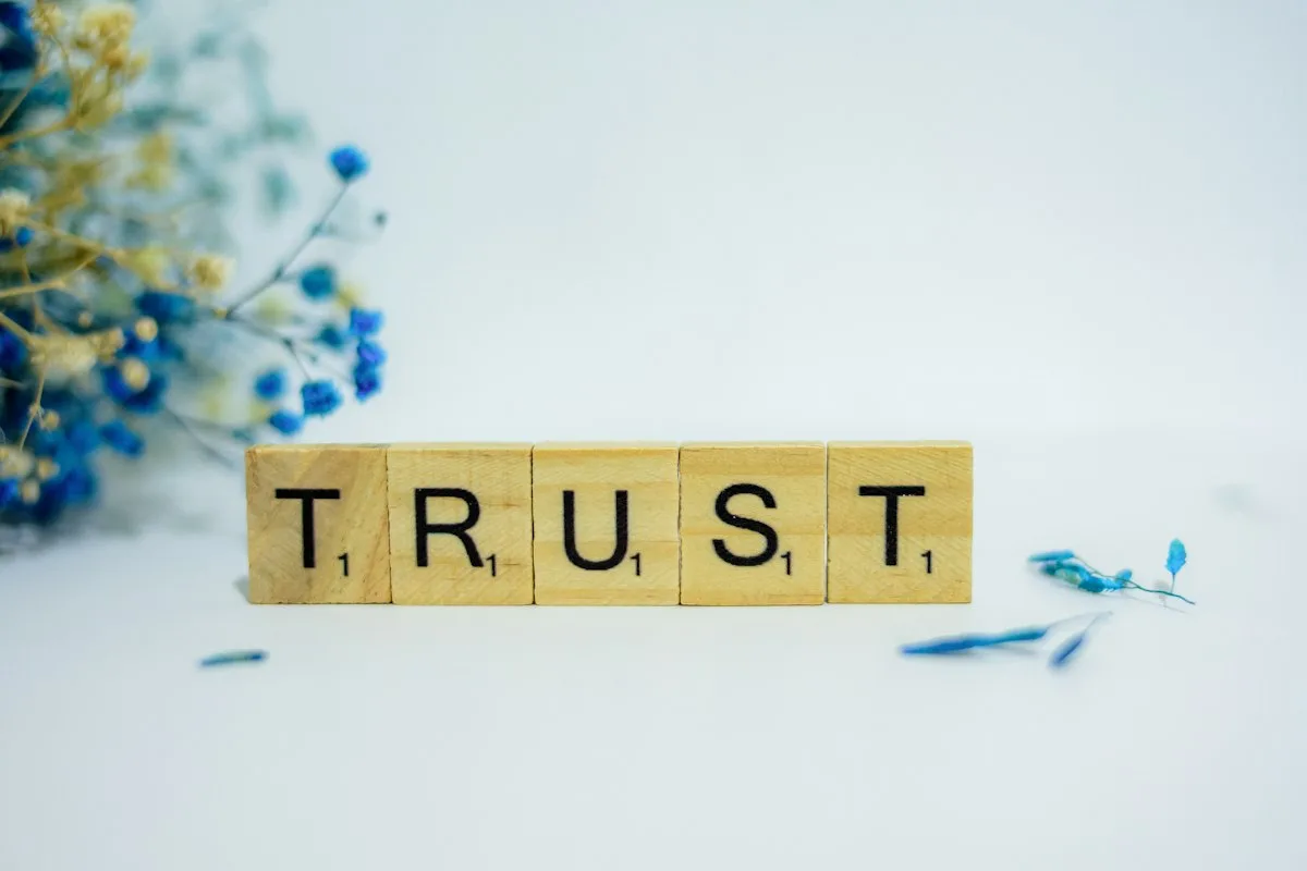 A wooden block reading 'trust', surrounded by flowers.