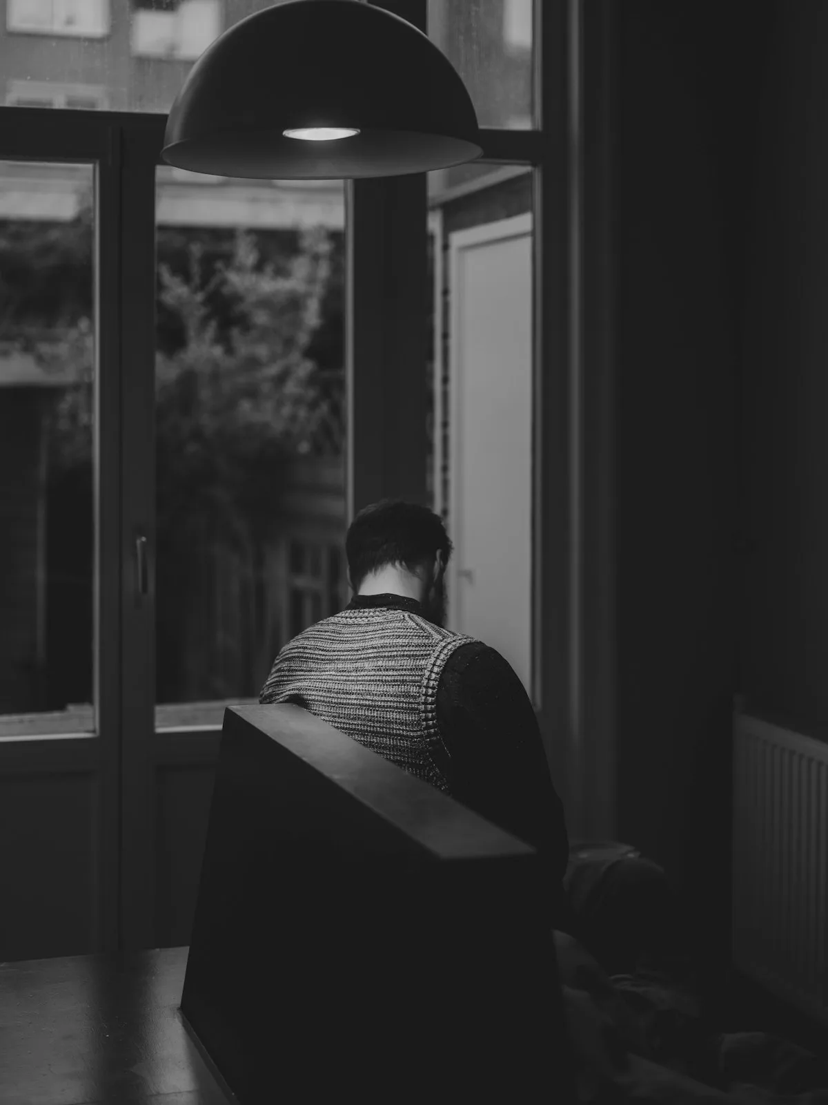 Someone sitting alone, looking out the window at night.